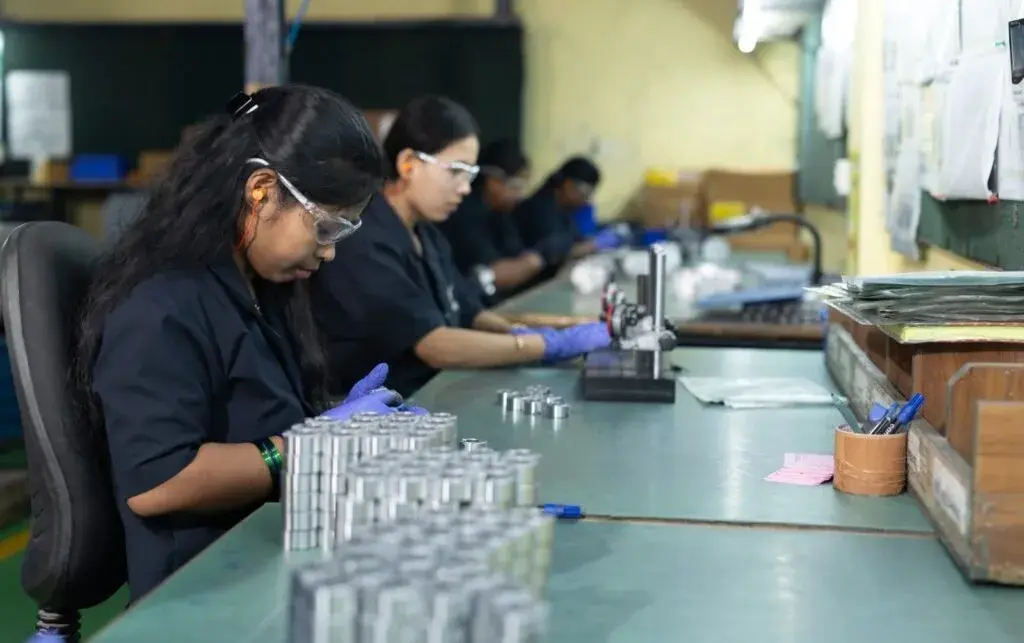 Operators in safety glasses and gloves inspecting machined parts